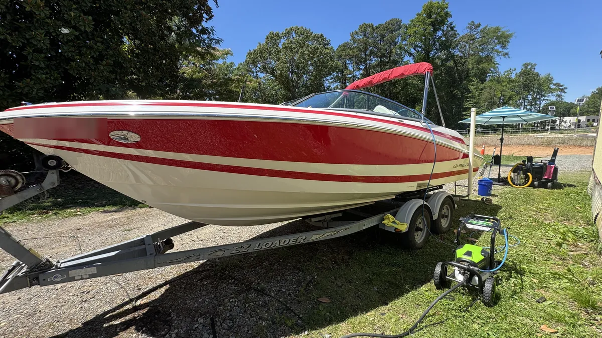 Red Regal bowrider on its trailer during a wash-down, with our pressure washer beside it