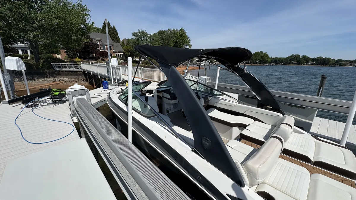 Dirty Work pressure washer and hoses set up on a private dock beside a wake boat and lake house